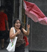 A  woman holds her umbrella tight against powerful gusts of wind as Typhoon Usagi approaches in Taipei, Taiwan, Saturday.